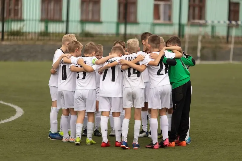 Young soccer team huddles for motivation before match, promoting teamwork and unity.